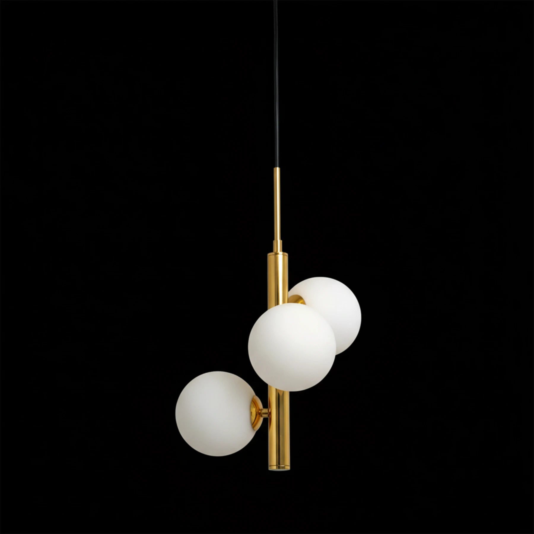 Modern pendant light with three glass bulbs and gold fixture on a black background